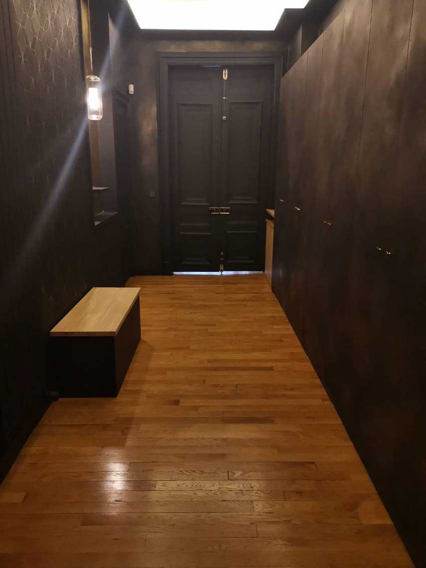 Entrée avec murs foncés et banc en chêne — rénovation Paris